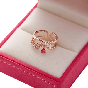 Rose gold flower ring with crystals and red teardrop gem in a pink velvet box