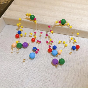Colorful resin bead geometric earrings with gold accents on a beige display tray