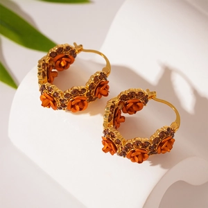 Detailed view of orange rose earrings with amber rhinestones and gold plating