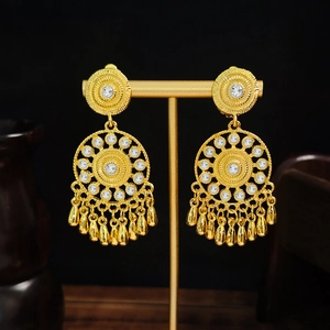 Detailed shot of bohemian gold teardrop tassel earrings with crystals on a display stand