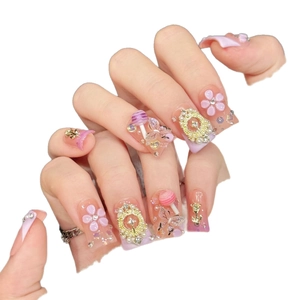 Pink gradient press-on nails with 3D floral accents and sugar-themed charms on long square nails