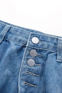 Détails de la braguette à plusieurs boutons et texture denim sur un jean bleu large