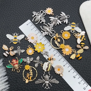 Detailed macro shot of alloy bee and flower charms next to a ruler for size scale