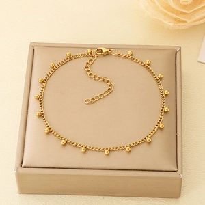 Détail d'une chevillère en acier inoxydable doré 18k avec perles sur boîte beige