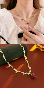 Macro detail of strawberry pendant necklace with golden chain and colorful gemstone charms