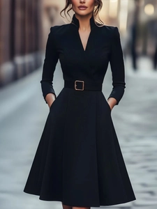 Detail of elegant black V-neck dress featuring a waist belt with a golden square buckle