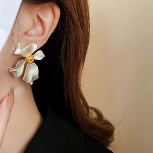 Close-up of vintage matte white flower earring with gold pistil worn on ear