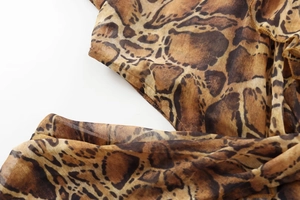 Detailed macro view of leopard print chiffon fabric texture and edge stitching on midi dress