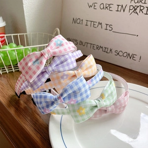 Colorful plaid bow headbands with floral patterns displayed on a decorative white plate