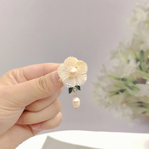 Macro shot of flower petal earring with pearl center and green enamel leaf detail