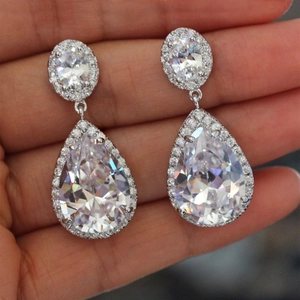 Elegant silver teardrop halo earrings featuring brilliant AAA cubic zirconia on palm