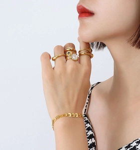 Dettaglio del bracciale a catena placcato oro 18k e anelli d'oro assortiti su una modella