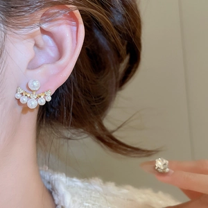 Close-up of elegant gold pearl earrings with sparkling zircons worn by a model