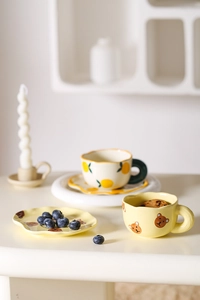 Close-up of cute ceramic coffee cups with bear and lemon patterns on saucers