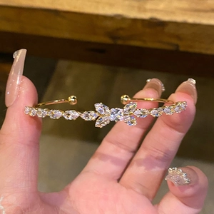 Detail of gold sun and moon open bracelet featuring a cubic zirconia butterfly motif