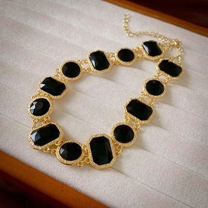 Detail view of vintage gold necklace with black gemstones on a velvet jewelry tray