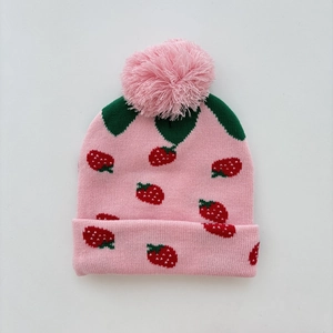 Detail showing soft pink knit texture and woven strawberry patterns with a fluffy pom-pom