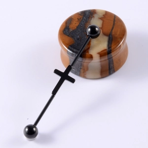 Macro view of black industrial barbell featuring a central cross pendant on stone base