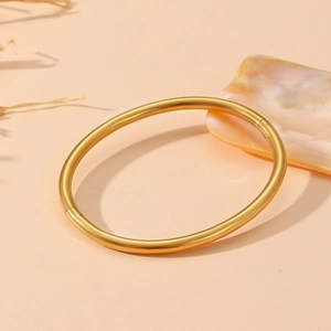 Detailed close-up of a polished gold stainless steel bracelet with buckle closure