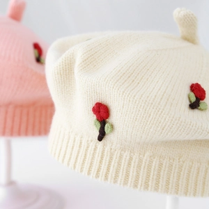 Close-up of knit beret with detailed floral embroidery and warm ribbed texture