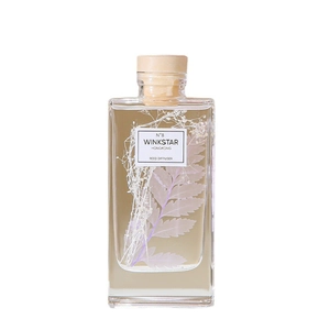 Square glass reed diffuser with preserved flowers and wooden stopper on white background