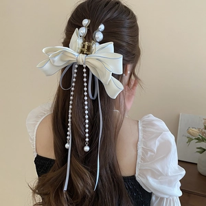 Close-up of hair claw featuring oversized cream bow and pearl fringe on hair