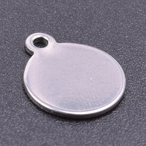 Close-up of a silver polished stainless steel round charm with a hole on black texture