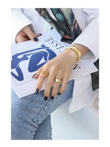 Lifestyle shot of gold chain ring and heart mother-of-pearl ring on hand with Matisse book