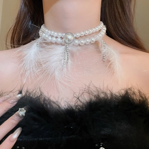 Detail of a double-layer pearl choker featuring white feathers and rhinestone tassels