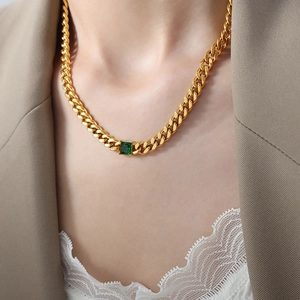 Baroque emerald zircon gold Cuban link necklace shown on a model neck with chic blazer