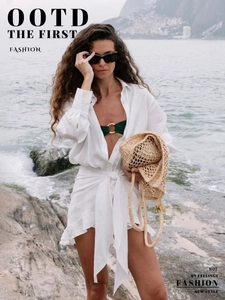 Close-up of beach resort outfit with white linen shirt and green bikini details