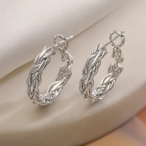 Boucles d'oreilles créoles torsadées en argent poli au fini géométrique sur marbre
