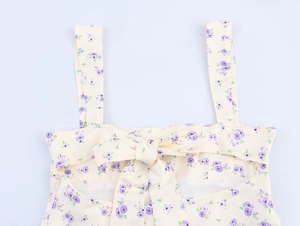 Détail de robe satinée à fleurs avec nœud et fermeture éclair latérale en crème et violet