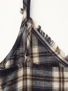 Detail of adjustable straps and fringed edges on the blue plaid summer dress