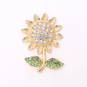 Golden sunflower brooch with white and green rhinestones isolated on white background