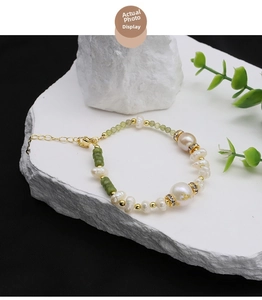 Detailed shot of freshwater pearl bracelet with green beads on stone pedestal
