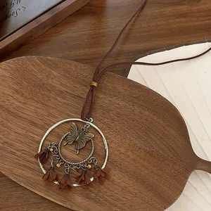 Detail of bohemian necklace featuring bronze butterfly ring and brown fabric petals