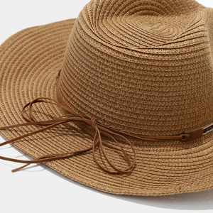 Close-up of brown straw sun hat featuring a delicate leather rope and bow detail
