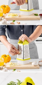 Detail view of a 4-sided stainless steel grater with green handle and white food collector