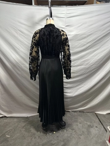Detail of sheer floral lace back and pleated skirt texture on a black maxi dress