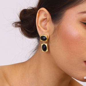 Macro view of gold plated stainless steel drop earrings with black geometric gemstones
