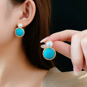 Detail of vintage gold earrings with white pearl and round turquoise stone pendants