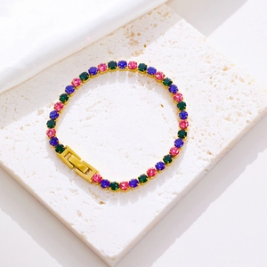 Detail of colorful cubic zirconia gold tennis bracelet on white textured stone surface