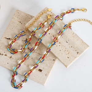 Colorful enamel gold chain necklace with lobster clasp on beige stone background