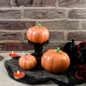 Tre candele a forma di zucca arancione di varie dimensioni su pizzo nero decorativo