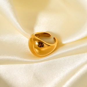 Close-up of a polished gold-plated chunky dome ring on elegant pleated silk fabric