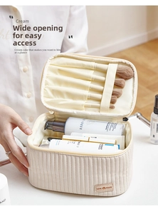 Detail of a cream quilted makeup bag showing brush slots and large interior capacity