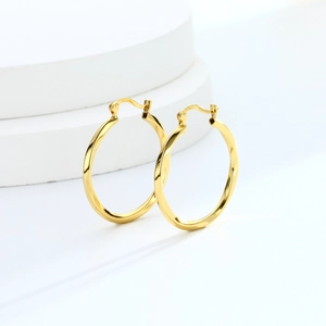 Detail of twisted S925 sterling silver hoop earring with gold finish on stone display