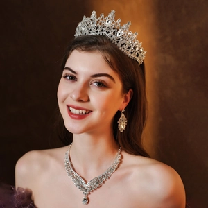 Close-up of bridal jewelry set with silver crown, necklace, and earrings on a model