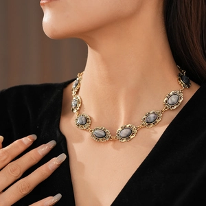 Close-up of vintage gold necklace with dark oval resin gemstones worn by model